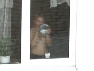 A Hot Topless Chick Puts On Her Makeup By A Window